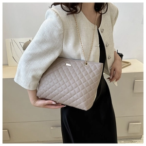 Detail of light brown quilted leather bag with classic diamond stitch and gold chain