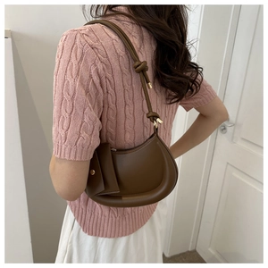 Detailed view of dark brown crescent underarm bag with knot strap and small pouch