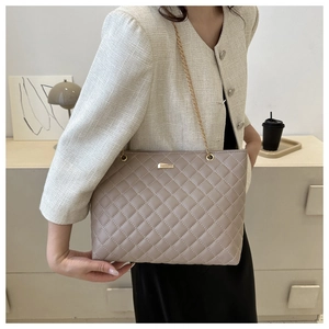 Close-up of taupe quilted shoulder bag with gold chain strap and elegant metallic detail