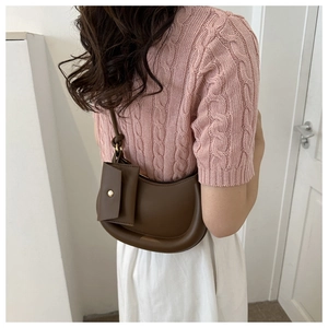 Brown crescent shoulder bag with matching coin pouch shown on model in minimal studio