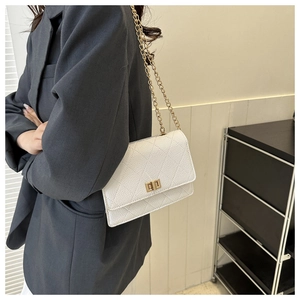 Detail of white quilted crossbody bag with golden twist lock and chain strap on model