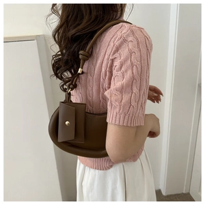 Close-up of brown crescent underarm bag with a side flap pocket and knotted shoulder strap