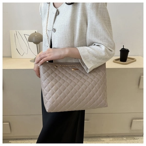 Detailed close-up of beige quilted shoulder bag featuring gold chain and metallic buckle