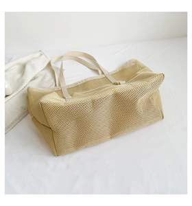 Detail view of beige mesh beach tote with reinforced handles on soft white texture