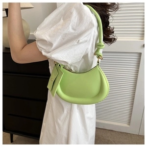 Detail view of bright green crescent shoulder bag with matching mini pouch on white dress