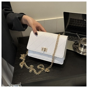 Close-up of white quilted crossbody bag with gold twist lock and metal chain strap