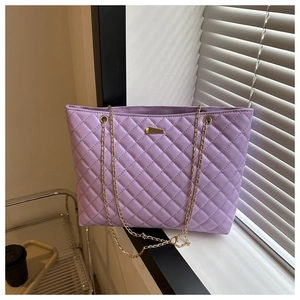 Detail shot of a lilac quilted chain tote bag with gold logo on a window sill
