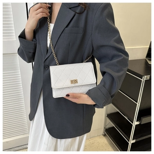 Detail of white quilted crossbody bag featuring a golden metal twist lock and chain strap