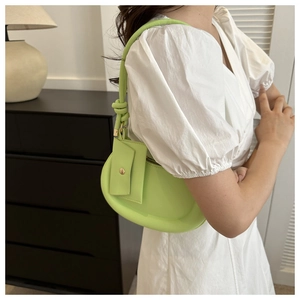 Detail of neon green underarm bag with unique knotted strap and front card slot