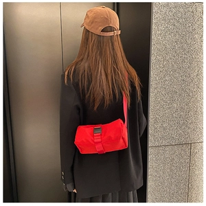 Detail of red waterproof gym bag with black buckle closure and adjustable shoulder strap