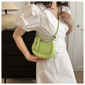 Model wearing a light green crescent shoulder bag with a mini pouch detail on the side