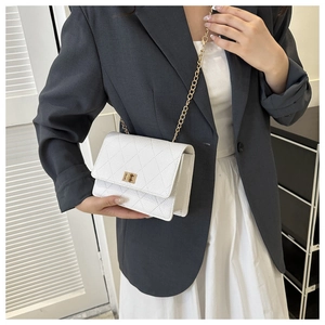 Close-up of classic white quilted crossbody bag with gold chain and metal lock on a model