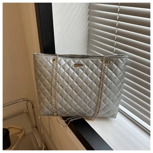 Detail of silver quilted tote bag with metallic finish and gold chain shoulder straps