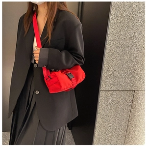 Detail of red waterproof nylon crossbody bag with black buckle and wide shoulder strap