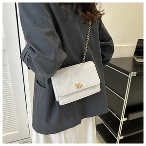White quilted crossbody bag with gold chain strap shown on model in office setting