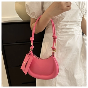 Detail of bright pink hobo bag with knotted handle and matching mini pouch accessory