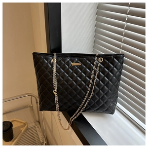 Detailed view of black quilted leather tote bag with gold chain and metal hardware