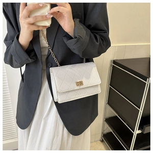 Detail of white quilted leather bag with gold chain strap and elegant metal twist lock