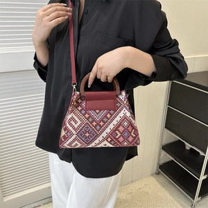 Ethnic geometric pattern handbag with wooden handle and red leather strap, crossbody view
