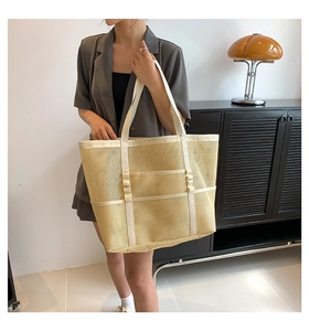 Detail of a large pale yellow mesh beach tote bag with cream-colored webbing straps
