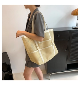 Detailed side view of a large beige mesh beach tote bag held by a model in a modern room