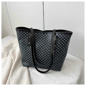 Detail of blue geometric dot print tote bag with black leather straps and gold rivets