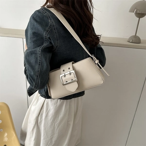 Minimalist beige baguette shoulder bag with silver buckle worn by a model in a modern room