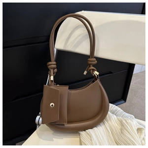 Detail of a brown leather crescent shoulder bag with knotted strap and small coin purse attachment