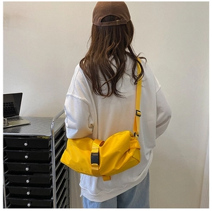 Rear view of a model wearing a bright yellow waterproof nylon sports crossbody travel bag
