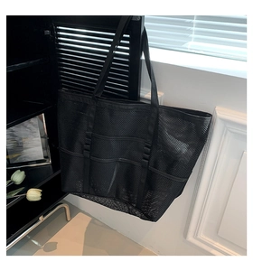Detail of a large black mesh beach bag showing breathable openwork and sturdy handles