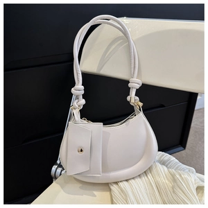 Close-up of white crescent crossbody bag with knotted strap and small pouch