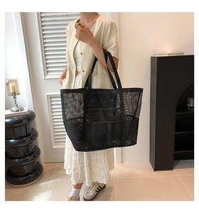 Close-up of black mesh beach tote with reinforced straps and multi-pocket design