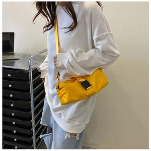 Detail of a bright yellow toast-shaped crossbody bag with a black buckle and strap