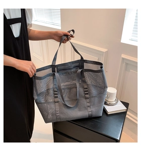 Detail view of a gray mesh tote bag with black straps and functional side pockets