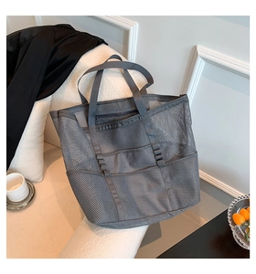 Detailed macro view of gray mesh beach bag with functional exterior pockets and zipper