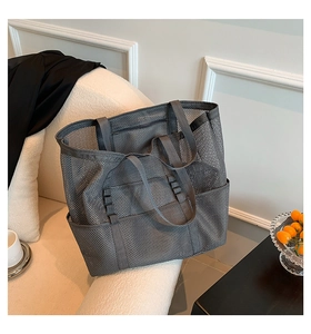 Detail of grey mesh beach tote bag featuring multiple exterior pockets on an armchair