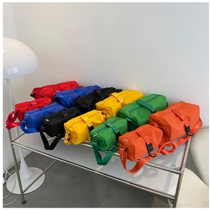 Various colors of nylon waterproof sports travel bags displayed on a modern metal shelf