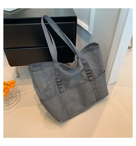 Macro view of gray mesh beach tote bag featuring wide shoulder straps and front pockets