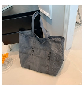 Detail of grey mesh beach bag with exterior pockets and durable woven handles