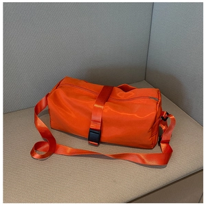 Detail of a bright orange sports gym bag showing the buckle strap and nylon texture