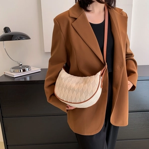 Minimalist beige quilted crescent bag with brown leather trim shown by a model