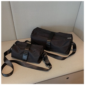 Detail of two black nylon cylinder duffel bags with buckle straps and adjustable shoulder belts