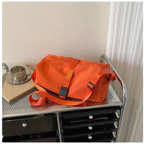 Close-up of orange waterproof sports bag with adjustable strap on a silver metal trolley