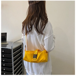 Detail of bright yellow waterproof nylon crossbody bag featuring large black buckle closure
