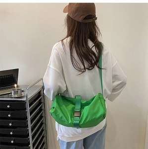 Green crescent crossbody sports bag with wide strap and silver buckle detail