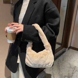 Sac à main en peluche beige élégant pour femme porté avec un manteau en laine noir chic