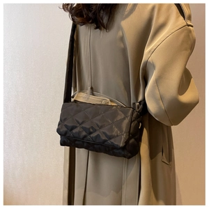 Gros plan du sac bandoulière en nylon noir matelassé avec surpiqûres losanges