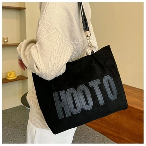 Détail du sac cabas en daim noir avec patch HOOTO et bandoulière en chaîne dorée chic
