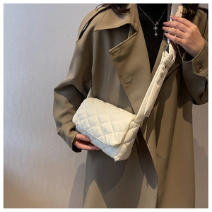 Détail d'un sac bandoulière blanc en nylon matelassé avec une large bandoulière