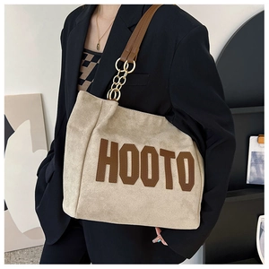 Détail du sac cabas en daim beige avec logo HOOTO et bandoulière en chaîne dorée